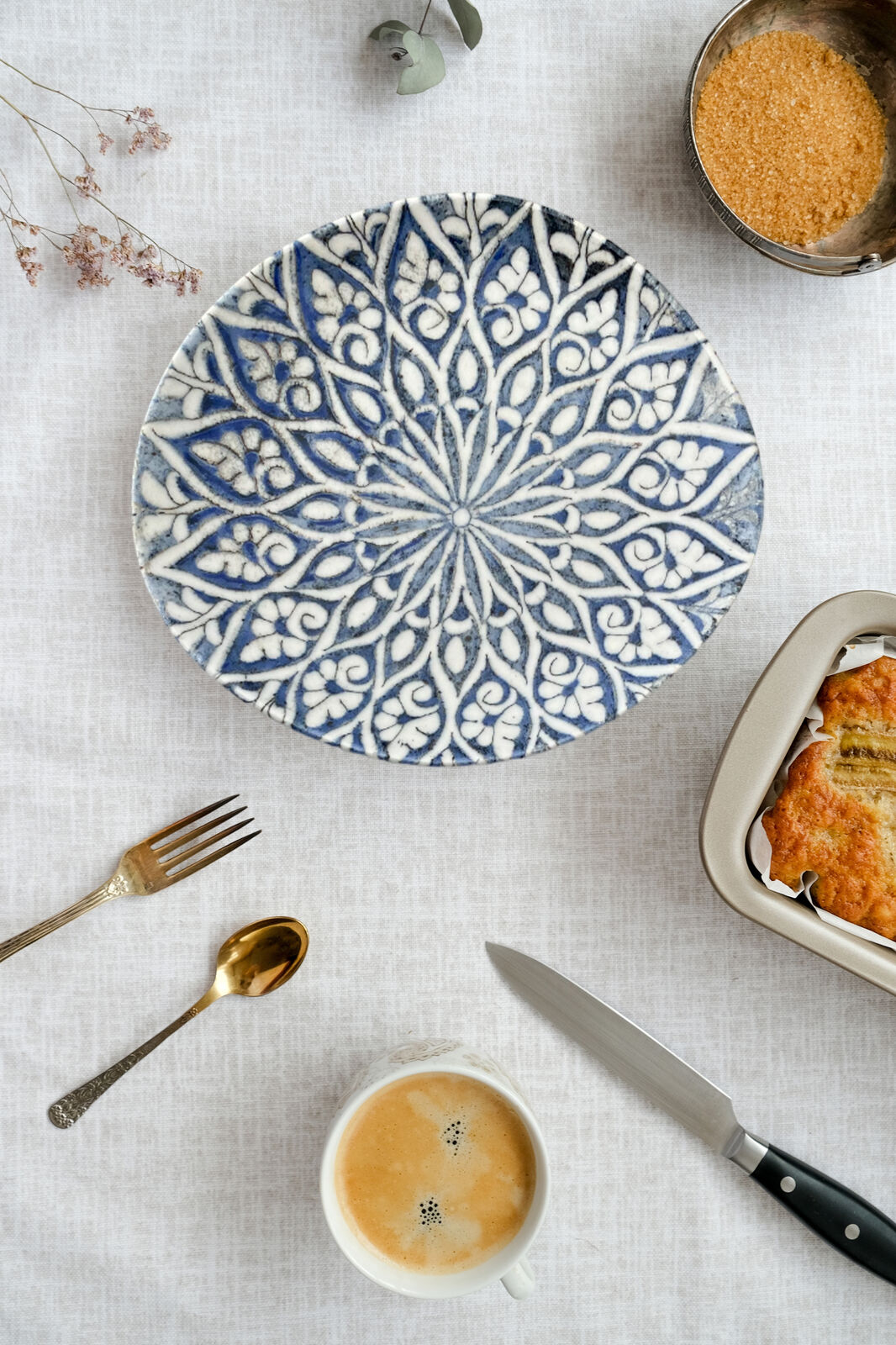 A ceramic plate with local designs shown among cutlery and food.
